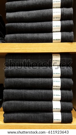 Stack of pants with size tag on shelf in store.