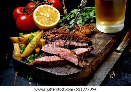 Steak with herbs and beer on a wooden background Royalty-Free Stock Photo #611977094