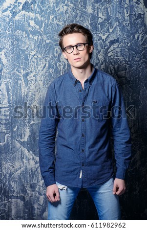 Handsome young man in casual jeans clothes and spectacles posing over grunge background. Men's beauty, fashion. Optics style.