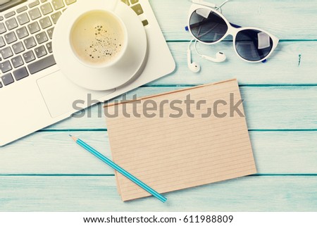Desk table with laptop, notepad, coffee and sunglasses on wooden table with sun beam. Workplace. Top view with copy space.