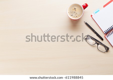 Office desk workplace with coffee cup, notepad and glasses on wooden background. Top view with copy space