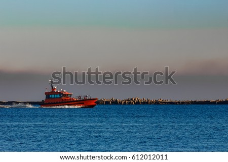 Red pilot ship moving past the breakwater dam in Riga, Europe