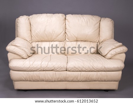 A grubby two seater cream colored leather sofa Royalty-Free Stock Photo #612013652