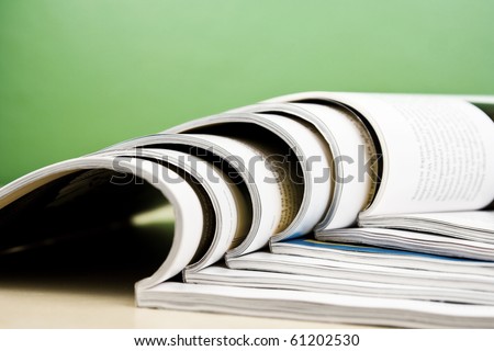 Open magazines in composition lying on table on green background