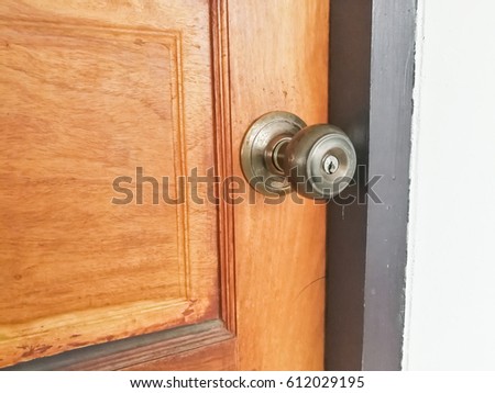 Aluminum door knob on the brown wood door 