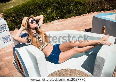 beauty woman lyeing on garden couch in hotel park. Summer vocation.