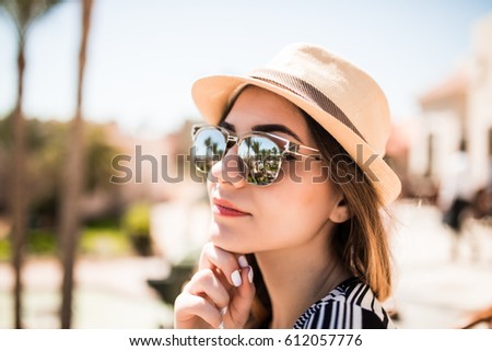 Portrait of beauty summer girl in hat and sunglasses on balcony of hotel room look at palms garden.