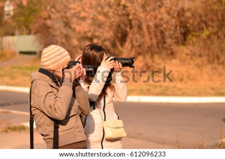 Two women photographers take photos together in the fall. Side view