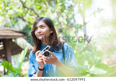 Hipster woman taking photos with retro film camera in flower garden of city park,beautiful girl photographed in the old camera