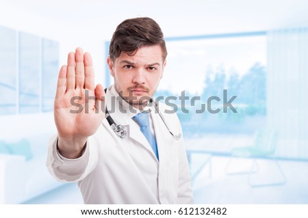 Angry male doctor in medical coat with repelling gesture with advertising area
