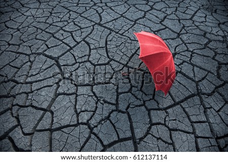 Red umbrella lies on the cracked earth. Drought.