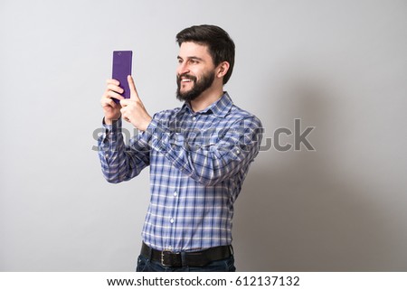 Bearded cheerful guy taking photos on smartphone