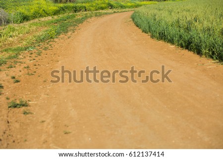 Dirt road at grass field background.