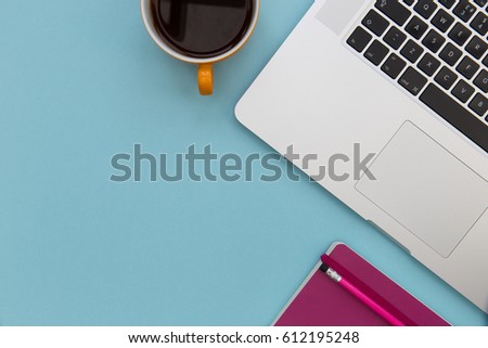 Coffee cup and laptop computer overhead on blue background