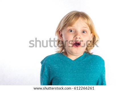 A 7 year old blonde child on whit background making faces for cameras.