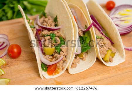 Mexican tacos with pork, pepper and tomatoes on the white wooden background. Shallow depth of field.