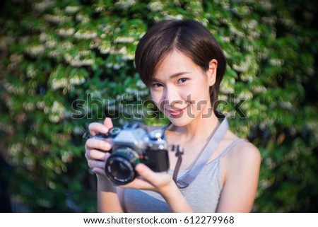 Young beautiful short hair Asian girl travels alone safely around in Thailand carrying a film camera to photograph the amazing places that she has visited.