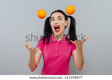 Woman with long straight hair, holding two oranges, looking up