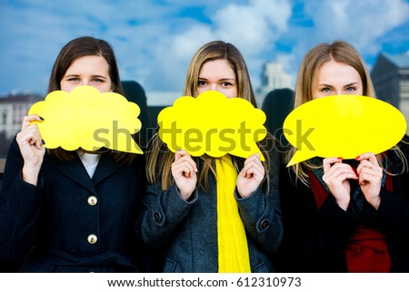 Three beautiful girls stand on the office building background holds a yellow plates, Empty space for text or message.