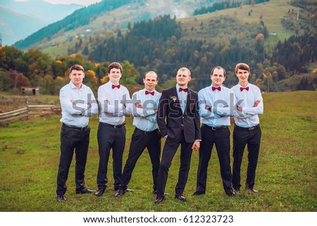 young groom and his funny friends groomsman posing for camera and having fun outdoor near mountains. Group of young men with bow tie. Cheerful friends. friends outdoors. Wedding day. 