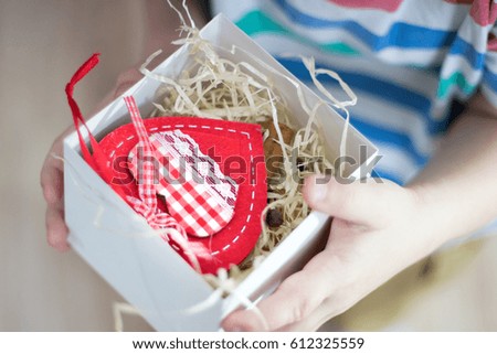 A child is holding a gift in hands a white box decorated with red ribbon 
