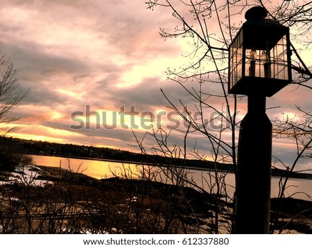 Vintage lamp post silhouetted against a storm cloud sky at sunset.   Sunset along the river. Light post