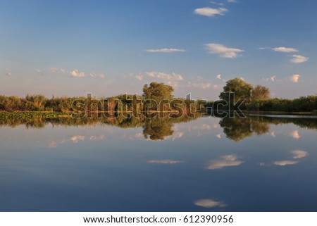 reflection of trees on a blue lake, Danube Delta, Romania