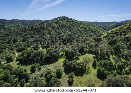 Line of California hills covered in the green of grass and trees during spring season.