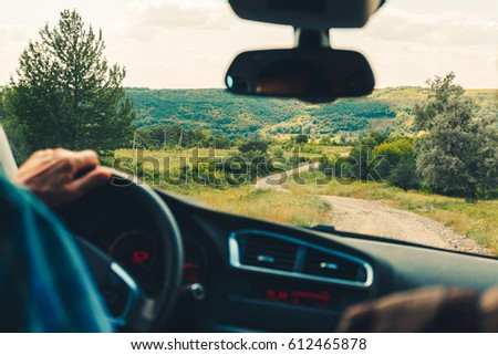 The view from the car on landscape. Travel in car. Man's, driver hand on the steering wheel controls Warm Toned picture, vintage tone.