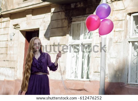 Outdoor portrait of a young beautiful lady with purple and pink balloons. Greetings birthday card concept