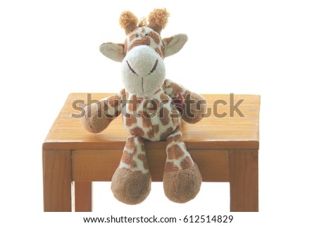 Giraffe doll sitting on wooden chair