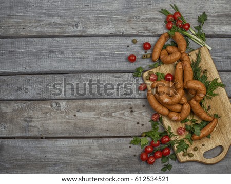 wooden surface with place for inscription and cutting board with handmade frankfurters, tomatoes, herbs, olives and spices lying on it