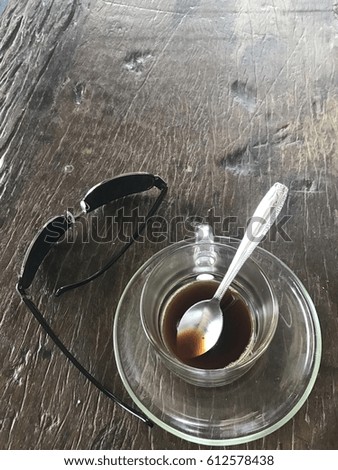 A cup of coffee drunk on a wooden table with sunglasses is placed parallel to the sign that it is ready for work.