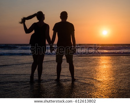 A guy and a girl are standing at sea in the sunlight