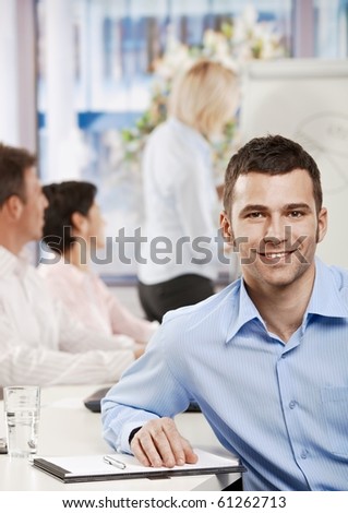 Happy young businessman in business meeting at office, looking at camera smiling.?