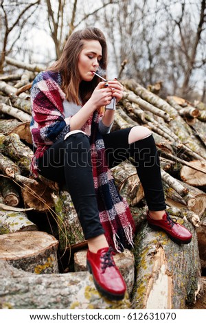 Young girl smoking cigarette outdoors background wooden stumps. Concept of nicotine addiction by teenagers.