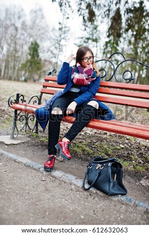 Young girl smoking cigarette outdoors sitting on bench. Concept of nicotine addiction by teenagers.