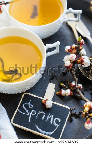 Cup of green tea and peach blossom on dark rustic table as a spring time concept
