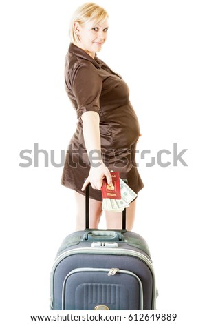 happy pregnant woman wearing brown dress stands with big suitcase, russian passport and wad of dollars