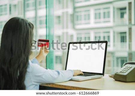 Young girl holding credit card and using laptop computer. Online shopping concept