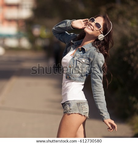 Image of young happy woman, listening music and having fun on the street. Lifestyle. Outdoor.