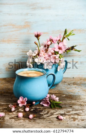 Coffee in old blue cup with pink blooming flowers on grunge wood background. good morning post card, banner design 