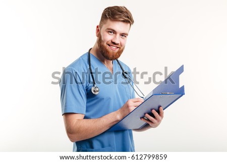 Portrait of a happy smiling doctor or nurse with stethoscope writing on clipboard and looking at camera isolated on the white background