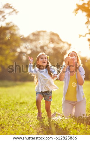 Cheerful girl chase shinny soap bubbles in nature
