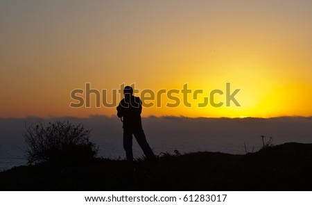 A  silhouette of photographer, taking picture of a  sunset