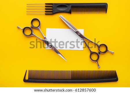 Professional hairdresser's scisors with business card on yellow background