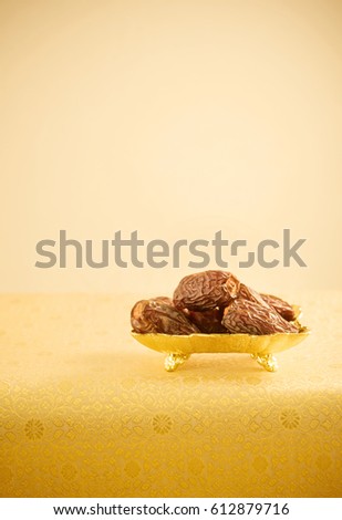 Ripen fine quality Arabian dates in a golden plate. Islamic festive background. Royalty-Free Stock Photo #612879716