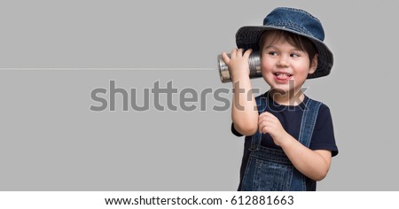 A small boy attached a telephone from a tin can to his ear Royalty-Free Stock Photo #612881663