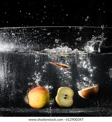 Two fresh apples falling into the water on the black background.