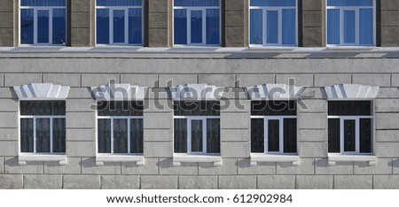 Texture of a glazed modern windows of a grey concrete building. Close-up photo of a concrete wall with plastic windows